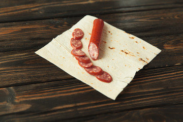 sliced salami on pita bread on wooden background