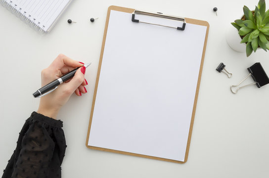 Business woman working with documents. Clipboard mockup template paperwork, financial reports,resume, brief, form, contract. Beautiful female hands in a black blouse with a red manicure holding a pen.