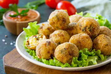 Arancini close-up - traditional Italian Rice Balls with Mozzarella and Sun-dried tomatoes, served with tomato sauce.