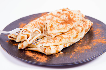 Pancakes stuffed with braised apples sprinkled with cinnamon eaten with a fork