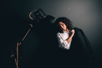 Beautiful curly girl in business clothes in the interior with a large wooden lamp