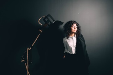 Beautiful curly girl in business clothes in the interior with a large wooden lamp