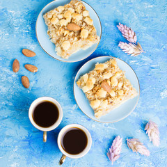 Two coffee cups, coffee grinder and apple pie on blue artistic background.