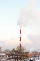 The smoke from the chimney of the boiler house. In the background of the city