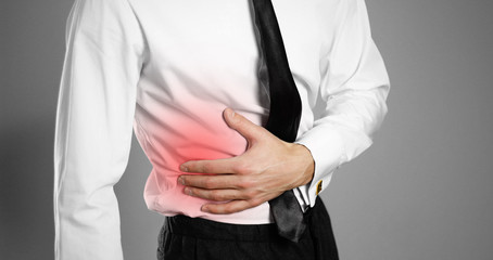 Businessman in a white shirt and tie holding his side. Pain in the liver. Syros liver. Isolated background