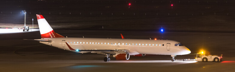 an airplane beeing towed at night at an airport