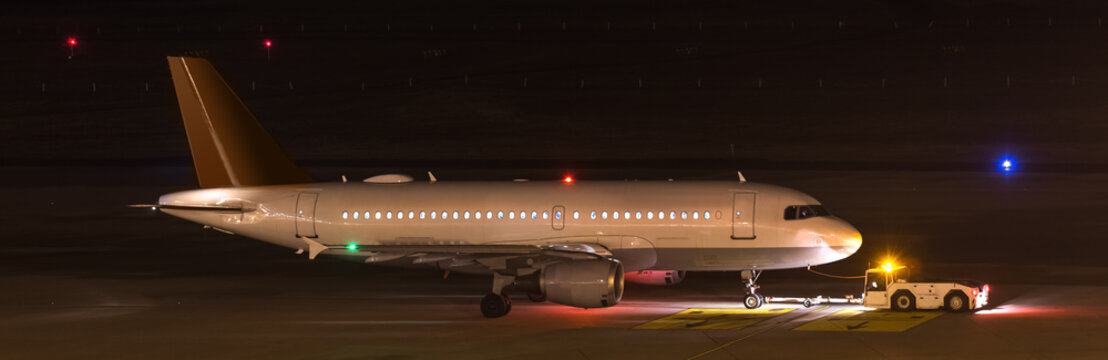 an airplane beeing towed at night at an airport