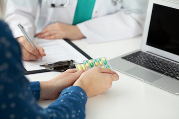  Close-up of a doctor and  patient  sitting at the desk while physician filling up medical history form. Medicine and health care concept