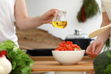 Closeup of human hands cooking in kitchen. Mother and daughter or two female friends cutting vegetables for fresh salad. Friendship, family dinner and lifestyle concepts