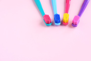 Colorful toothbrushes with selective focus on pink background. Toothbrush for personal routine morning  hygiene on neutral blurred backdrop. Dental plastic tool with empty space for image or text