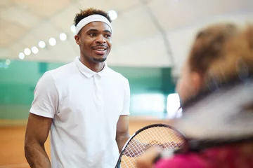 Poster Happy young tennis player in activewear and headband chatting to his playmate at break © pressmaster