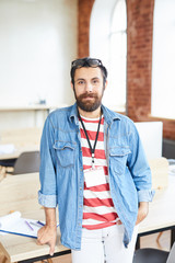 Fototapeta premium Young confident manager in casualwear standing by his workplace in modern office