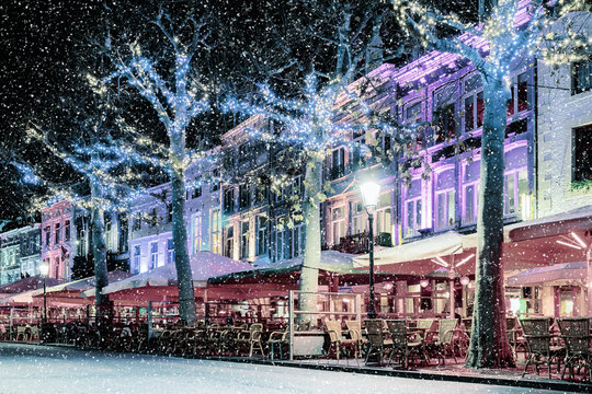 Bars and restaurants with snow and christmas lights on the famous Vrijthof square in Maastricht