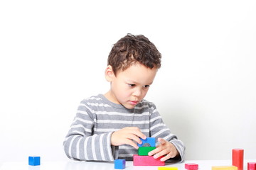 little boy testing his creativity by building towers with toy building blocks