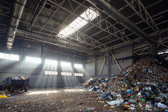 Modern plant for processing and sorting of municipal urban waste - evening sunlight in huge reception junkyard room, hangar for unloading waste from trucks and further processing sorting and reuse