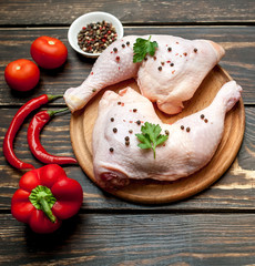 chicken legs with red pepper, tomatoes, parsley on a wooden background