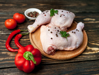 chicken legs with red pepper, tomatoes, parsley on a wooden background