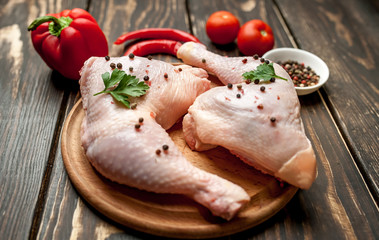 chicken legs with red pepper, tomatoes, parsley on a wooden background