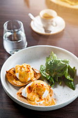 Lunch Time at Cafe. Sandwich with poahed egg with glass of water on table isolated close-up top view