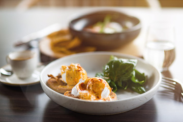 Lunch Time at Cafe. Sandwich with poahed egg on table isolated close-up blurred background