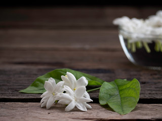 Fototapeta premium Jasmine floating in clear glass on wooden background.