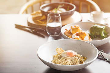 Lunch Time at Cafe. Pasta with poached egg on table isolated close-up blurred background