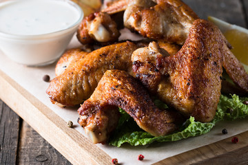 Close-up photo of bbq chicken wings with fries and beer. Barbeques meat with sauces, ketchup, mayonnaise. Fast and junk food concept. 