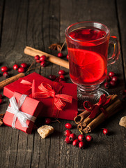 Red hot drink tea with spices, cinnamon, anise, fruits, brown sugar on an old wooden table with christmas presents. New Year and holidays concept. Mulled wine and glintwein.