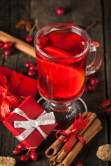 Red hot drink tea with spices, cinnamon, anise, fruits, brown sugar on an old wooden table with christmas presents. New Year and holidays concept. Mulled wine and glintwein.