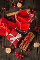 Red hot drink tea with spices, cinnamon, anise, fruits, brown sugar on an old wooden table with christmas presents. New Year and holidays concept. Mulled wine and glintwein.