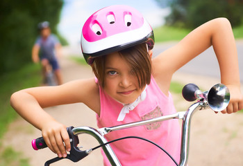 Naklejka premium Portrait of a little girl in a pink safety helmet driving her bike.