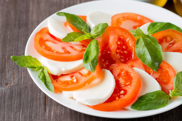 Close-up photo of caprese salad with ripe tomatoes, basil, buffalo mozzarella cheese. Italian and Mediterranean food concept. Fresh and healthy organic meal. Starter and antipasti. 