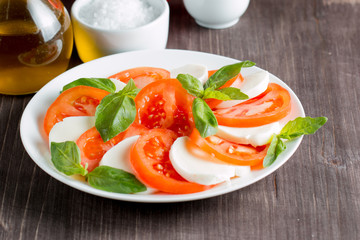 Close-up photo of caprese salad with ripe tomatoes, basil, buffalo mozzarella cheese. Italian and Mediterranean food concept. Fresh and healthy organic meal. Starter and antipasti. 