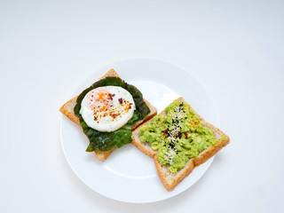 Appetizing bruschetta with egg and avocado on a plate. On the Sandwich, the avocado pulp and fried quail egg. Dark background. View from above. Close-up. Macro photography.