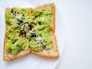 Appetizing bruschetta with egg and avocado on a plate. On the Sandwich, the avocado pulp and fried quail egg. Dark background. View from above. Close-up. Macro photography.