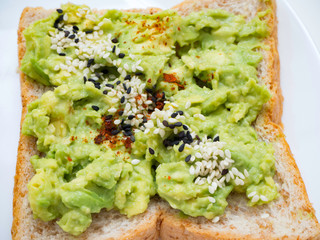 Appetizing bruschetta with egg and avocado on a plate. On the Sandwich, the avocado pulp and fried quail egg. Dark background. View from above. Close-up. Macro photography.