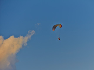 Paratroopers on motorized steamplanes fly against the blue sky with clouds