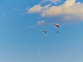 Paratroopers on motorized steamplanes fly against the blue sky with clouds