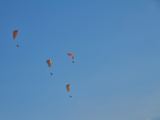 Paratroopers on motorized steamplanes fly against the blue sky with clouds