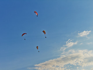 Paratroopers on motorized steamplanes fly against the blue sky with clouds