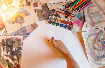 Physically handicapped woman painting with foot. Colorful paintings on the desk.