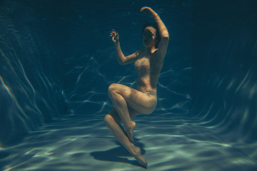 cute sporty girl swims underwater as a free diver in sheer jumpsuit alone