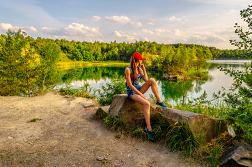 young girl in a jeans dress near forest lake in sunset