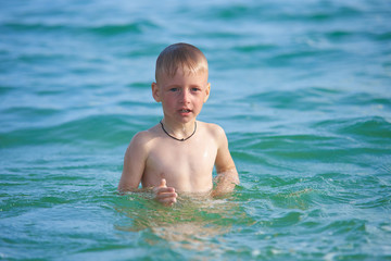Fototapeta na wymiar BOY 7 YEARS LEARN TO SWIM IN THE SEA