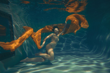 cute sporty girl swims underwater as a free diver in lingerie and mesh catsuit with rhinestones...