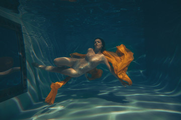 cute sporty girl swims underwater as a free diver in lingerie and mesh catsuit with rhinestones...