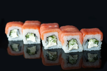 Tasty philadelphia roll with cucumber and cheese.Japanese rolls on black mirroring background