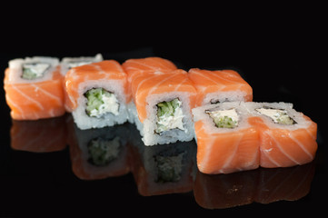 Tasty philadelphia roll with cucumber and cheese.Japanese rolls on black mirroring background