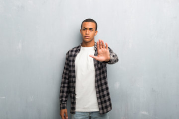 Young african american man with checkered shirt making stop gesture denying a situation that thinks...