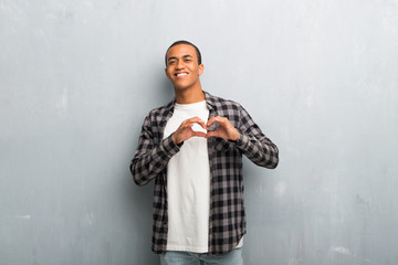 Young african american man with checkered shirt making heart symbol by hands